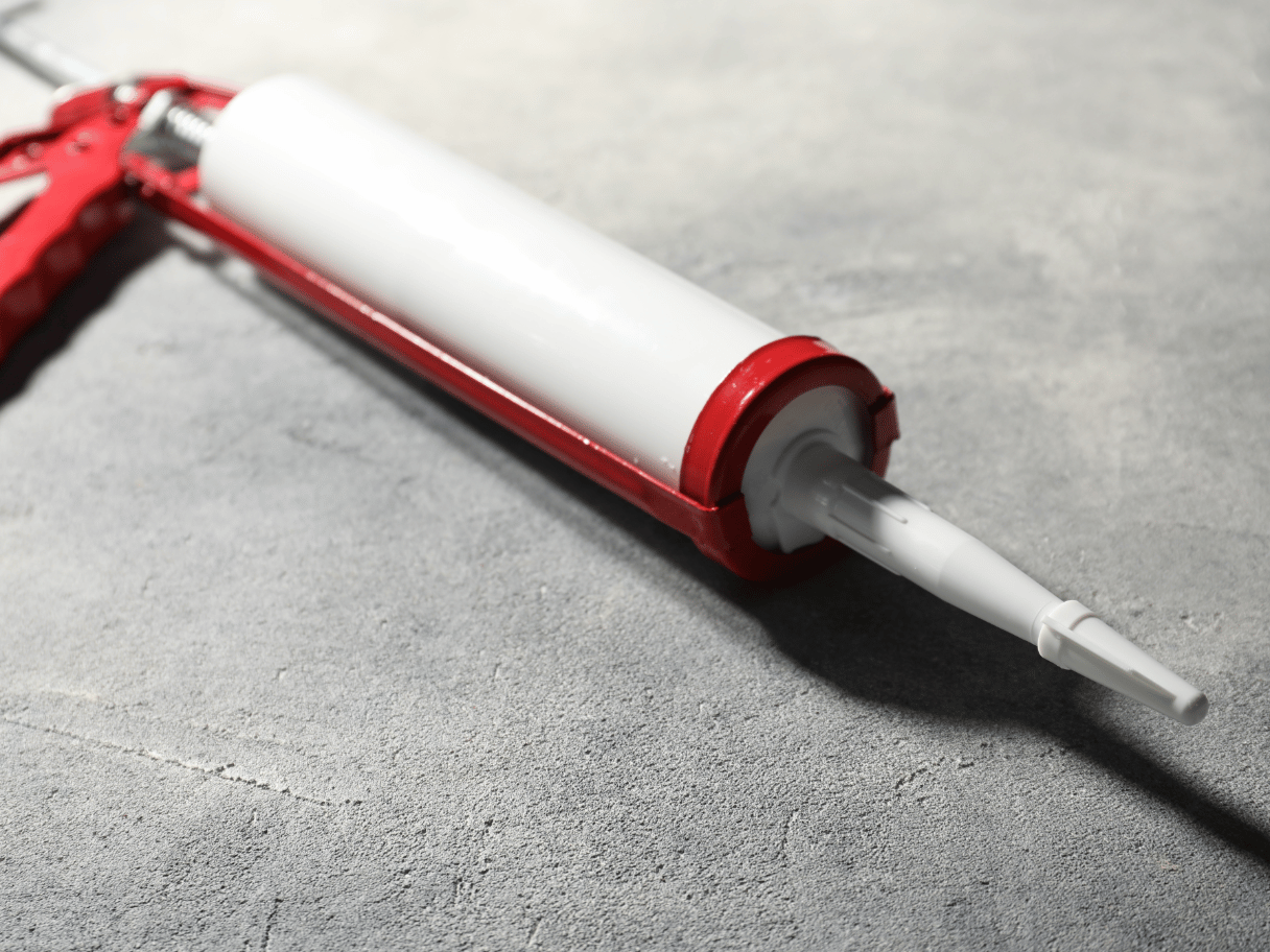 Caulking gun på betongulv
