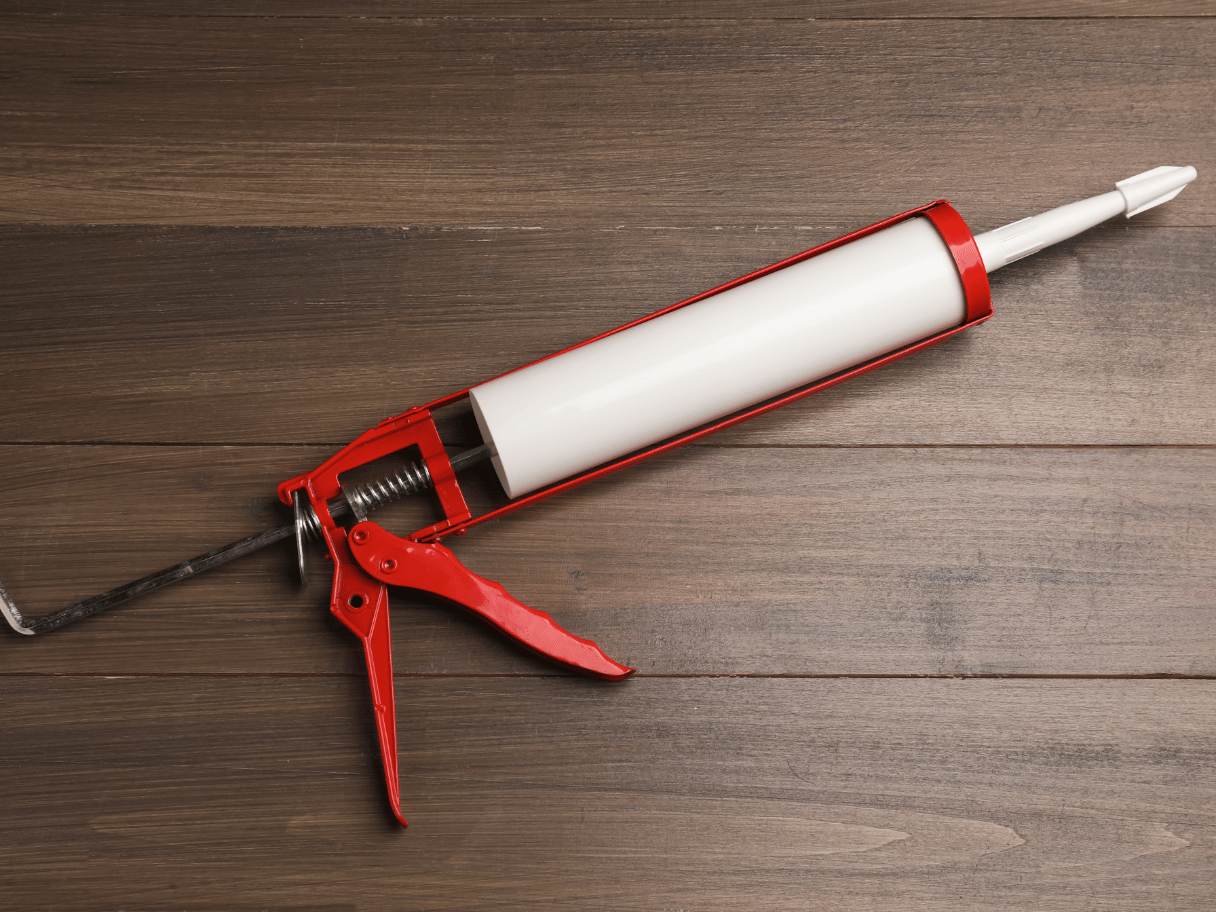 Caulking gun på trægulv