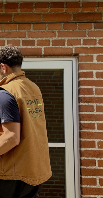 Prime Fuger-medarbejder ved vindue i arbejdstøj
