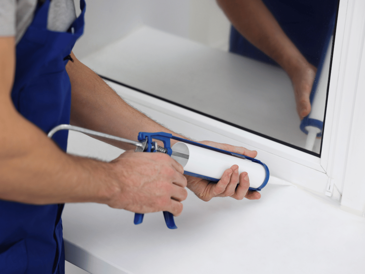 Fugning af vindue med blå caulking gun